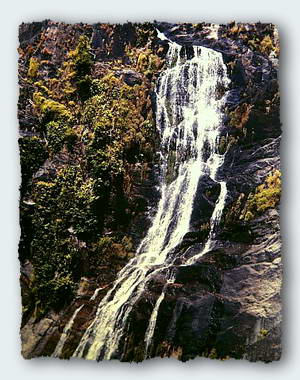 A waterfall spills down the rocky slope into the main river.